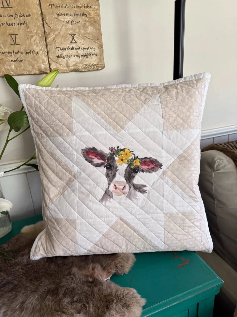 A quilted pillow features a watercolor calf wearing a yellow floral crown.