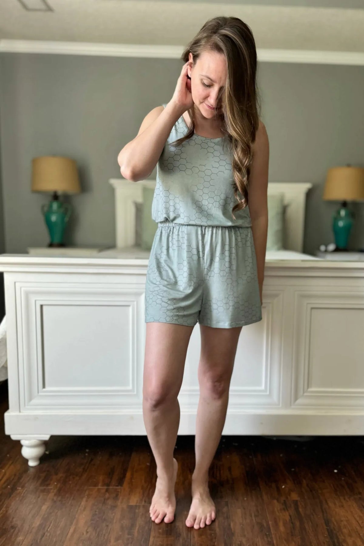 A woman models a light green romper with a subtle honeycomb pattern.