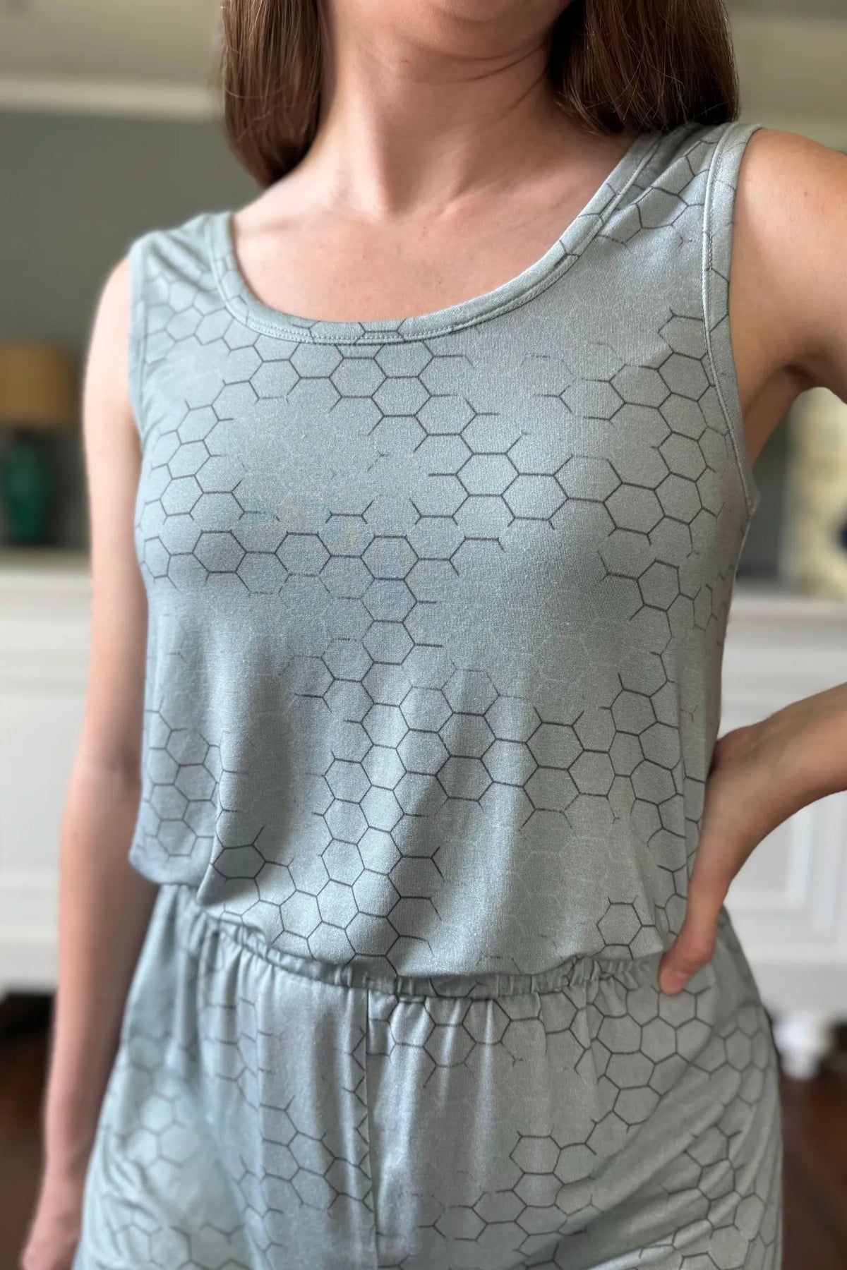 A person wearing a light green top and shorts with a honeycomb pattern.