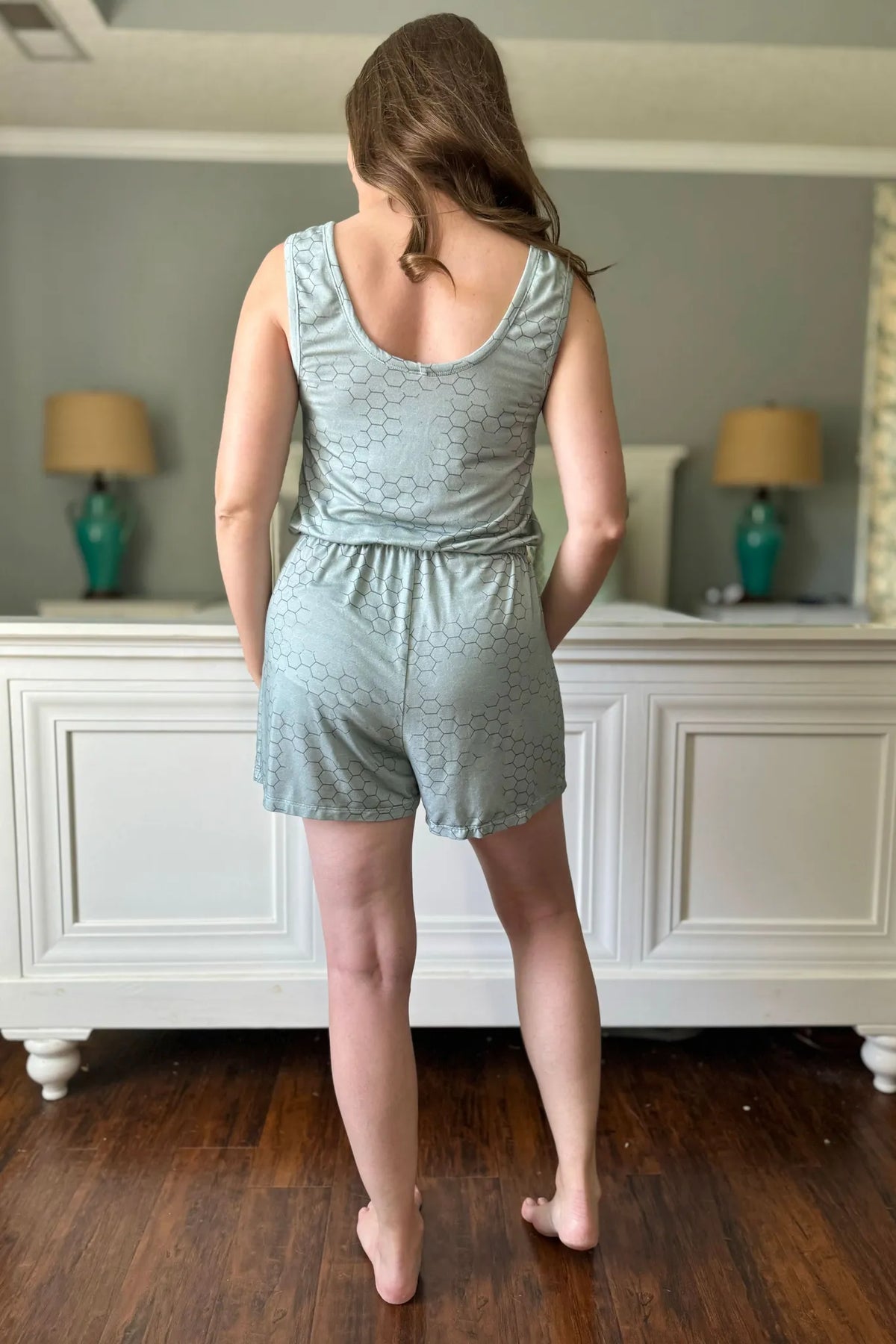 A woman from behind wearing a light green honeycomb patterned romper.