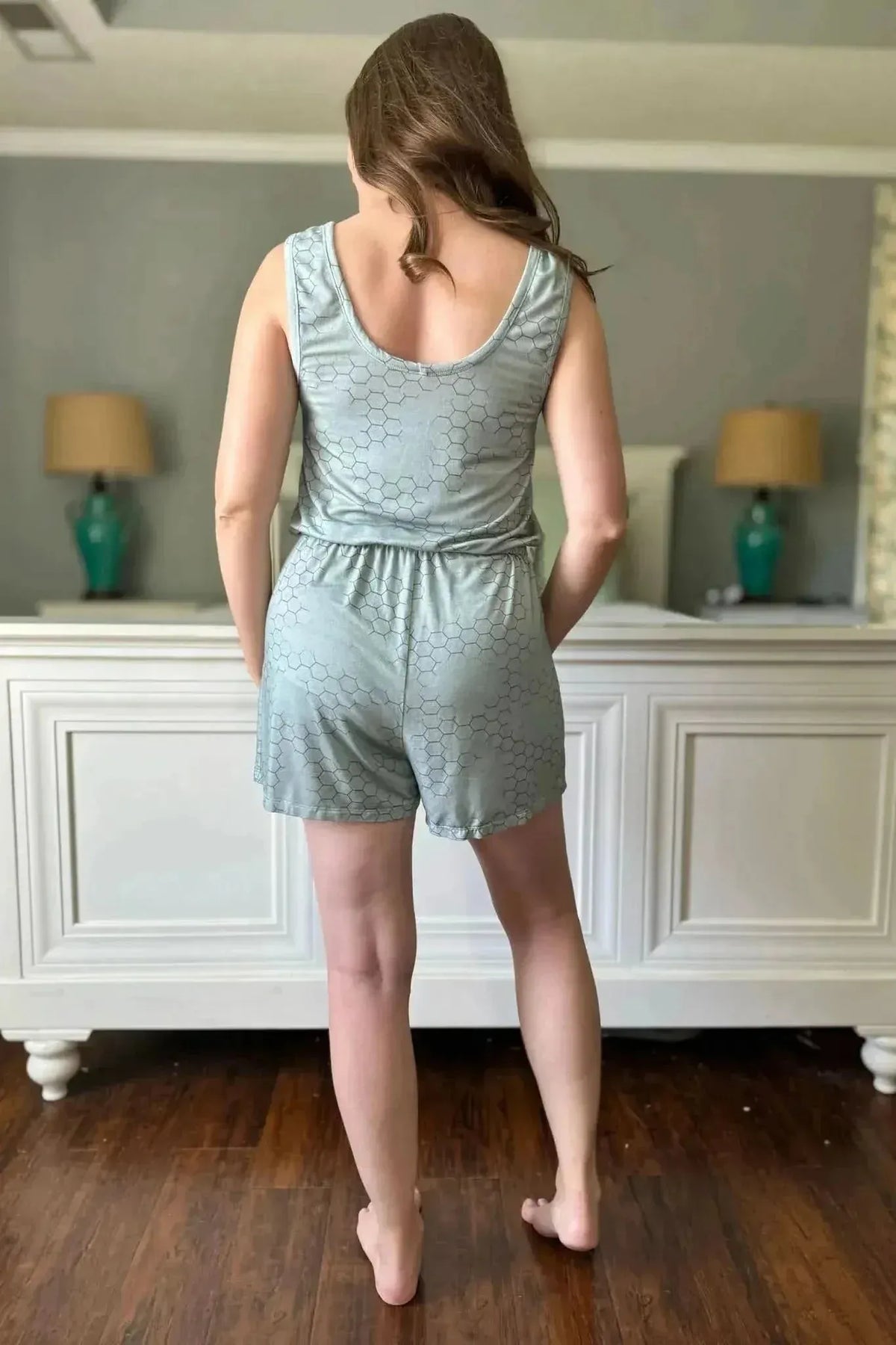 Back view of a woman wearing a light green honeycomb geometric print romper.