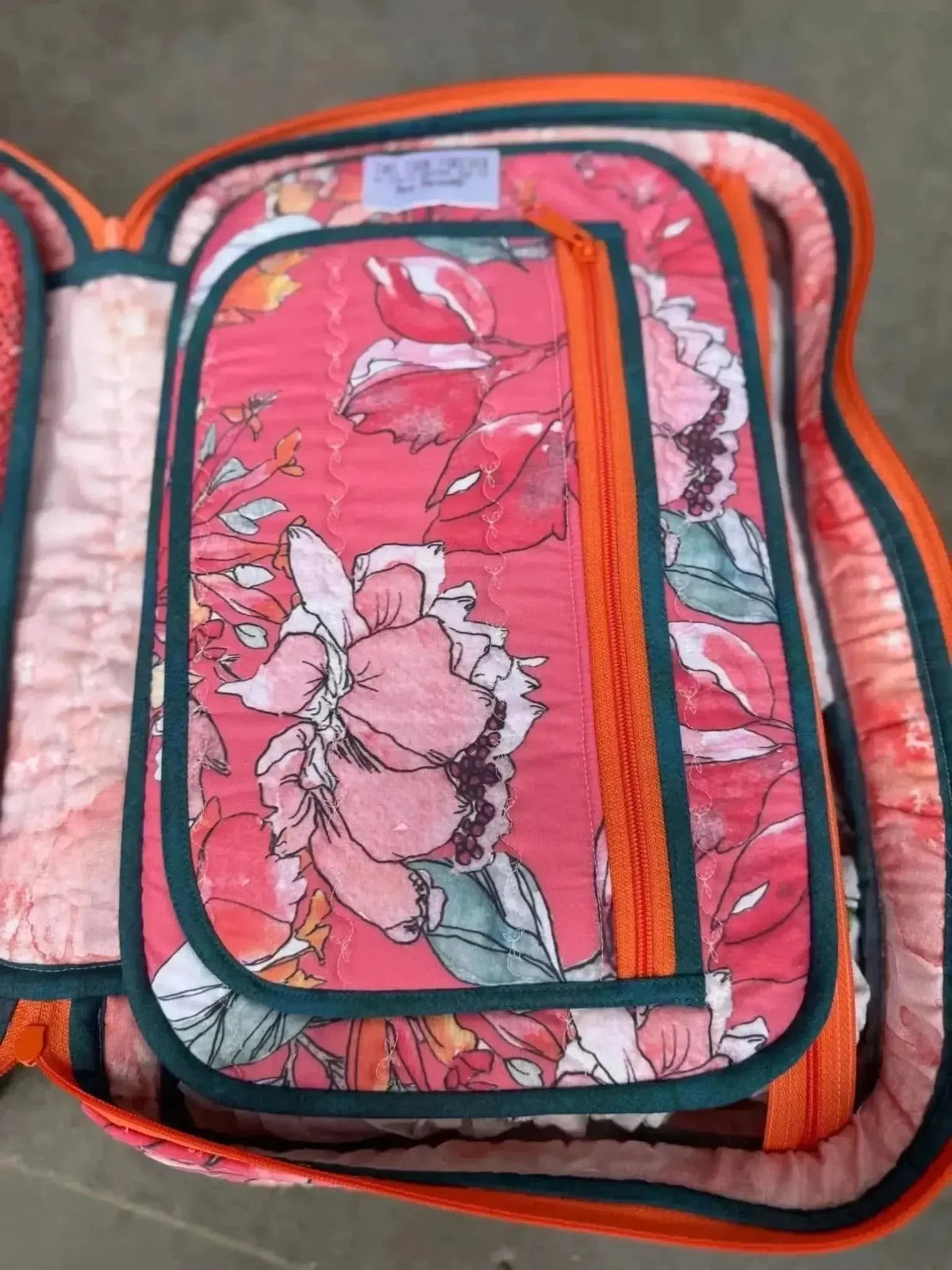 Open coral floral fabric with pink and green flowers on a red background.