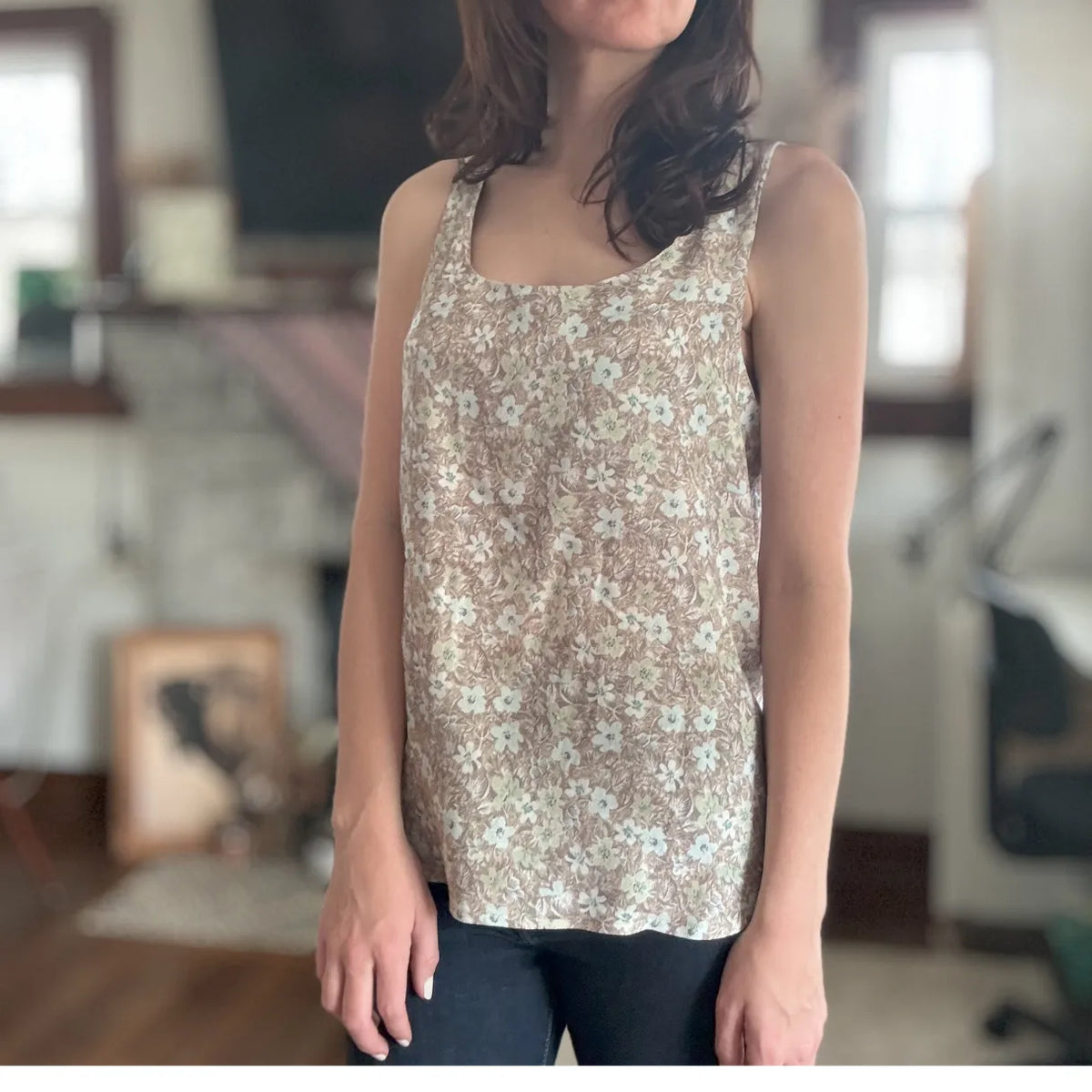 A person wears a brown floral print tank top.