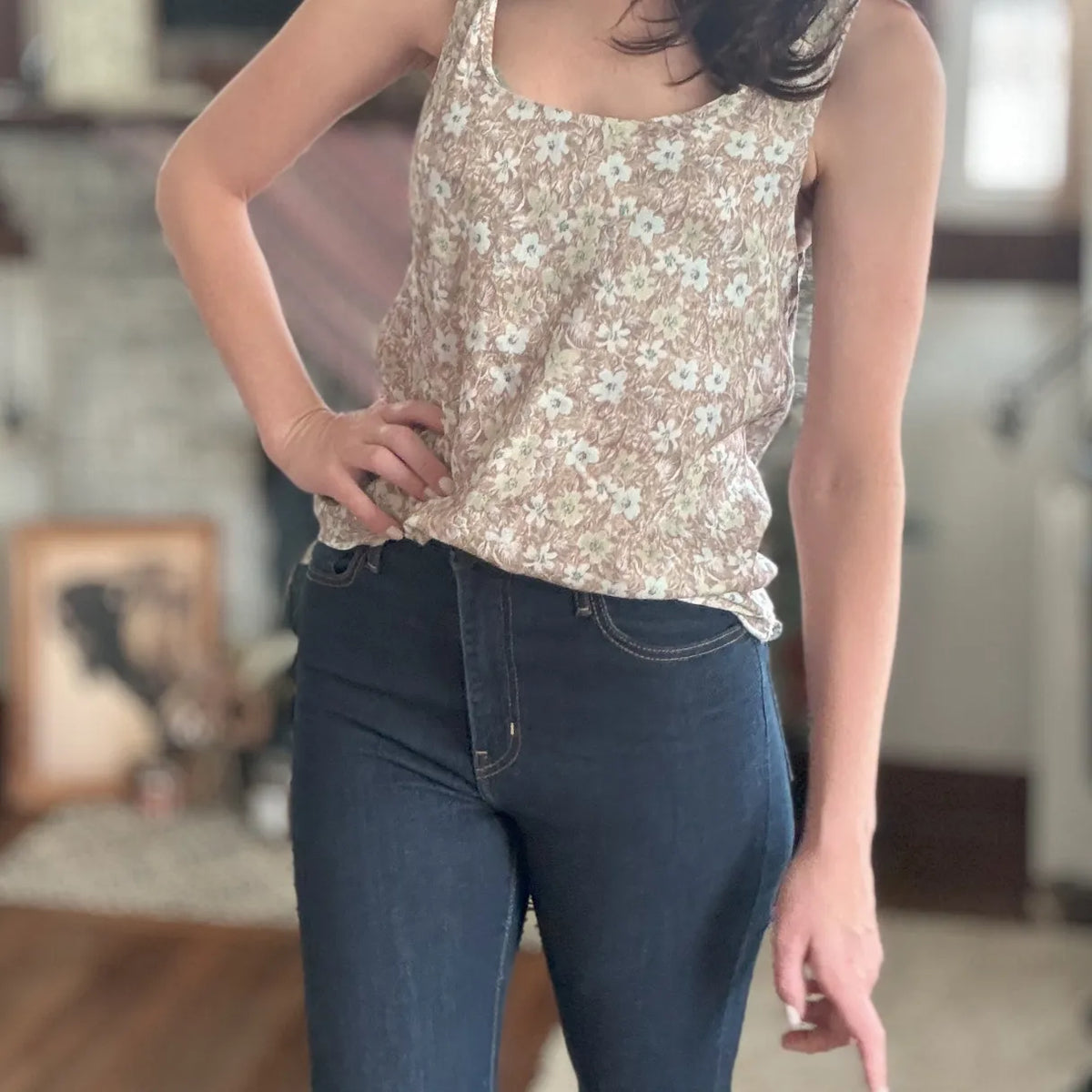 A person models a brown wallpaper leaves print tank top with dark jeans.