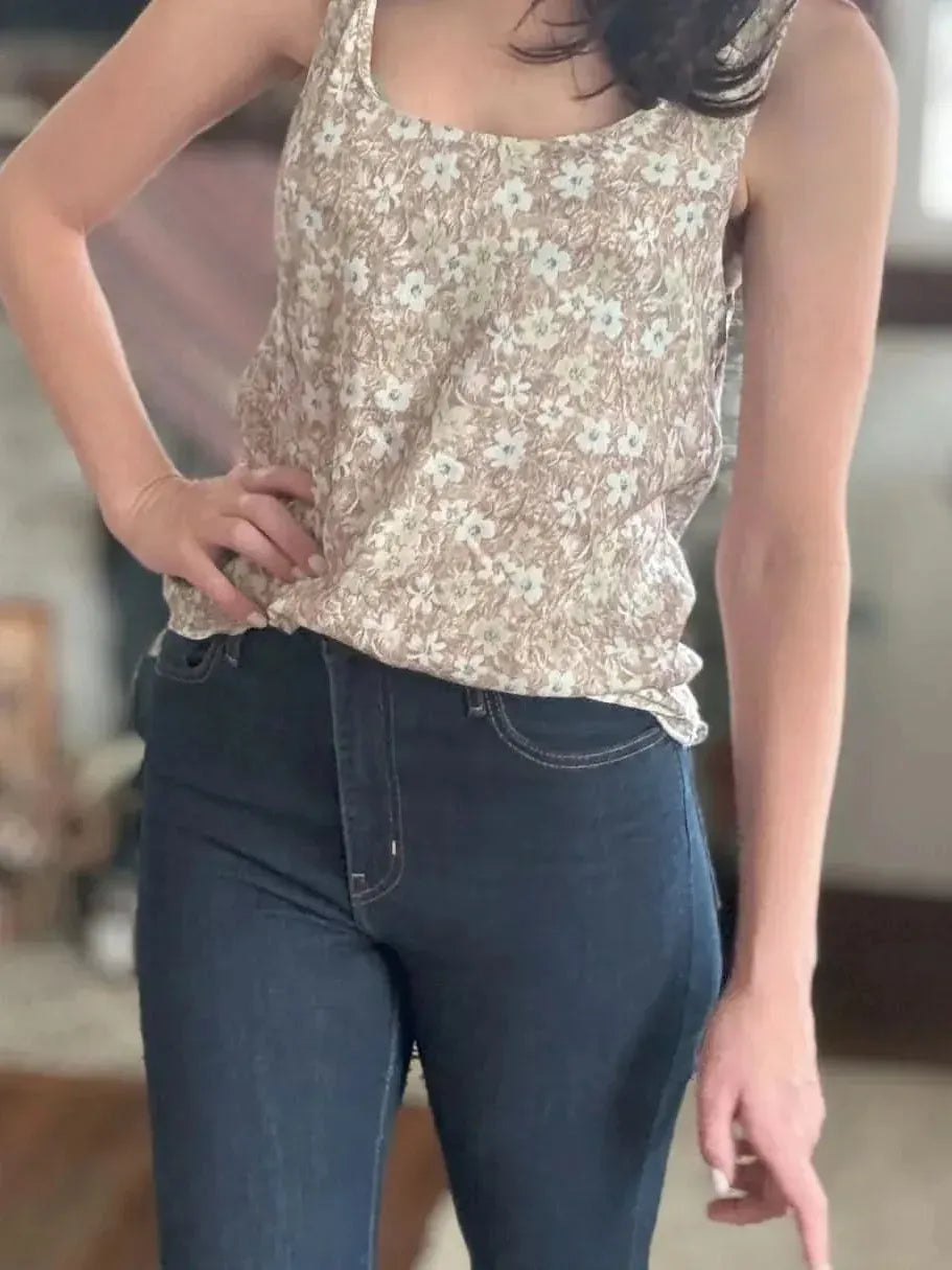A person models a brown wallpaper leaves print tank top with dark jeans.