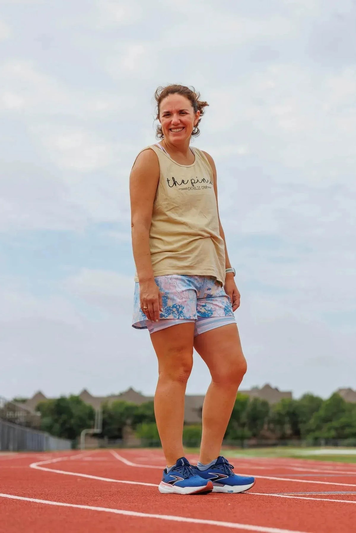 Woman wearing shorts in blue-pink abstract floral faith-based print on athletic track.