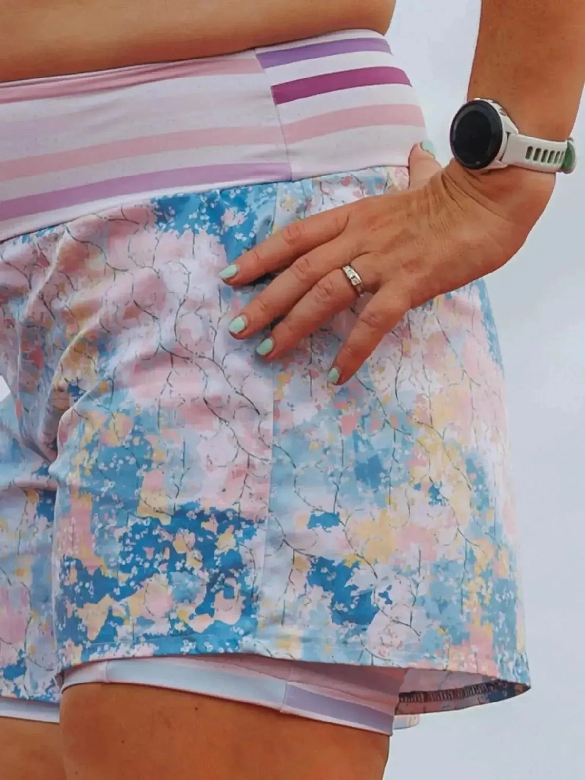 Close-up of women's blue and pink abstract floral stretch shorts on a model.