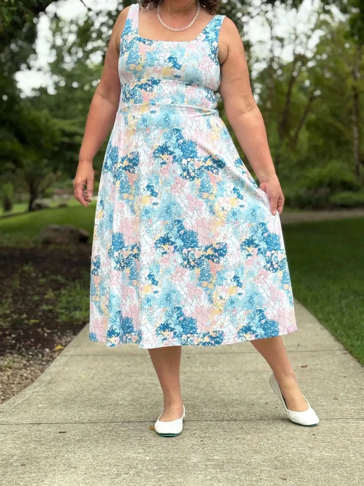 Blue and pink abstract floral fabric with faith-based print, shown as a sleeveless midi dress.