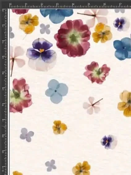 A light-colored fabric is covered with various pressed flowers in shades of blue, purple, and yellow.