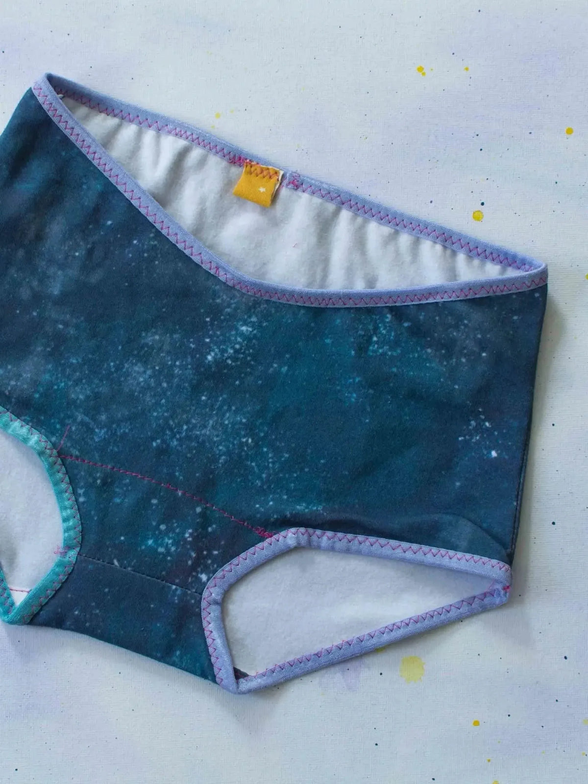 Purple women's underwear with starry celestial print on navy fabric.