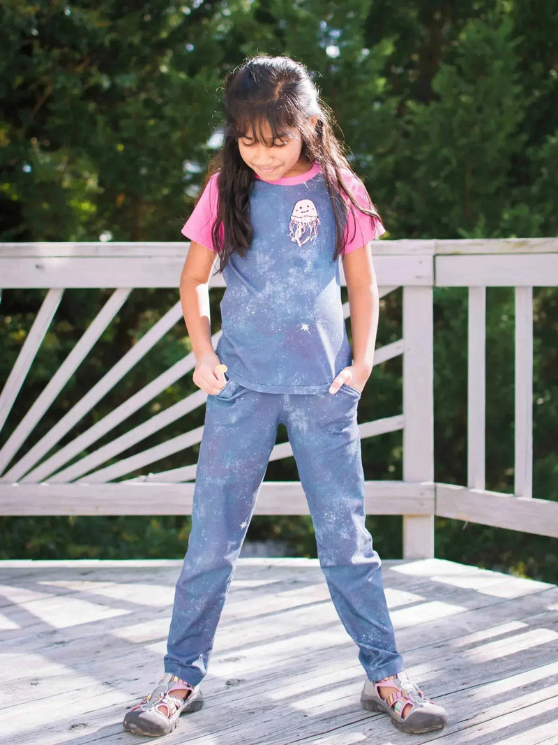 Girl wearing blue tie-dye outfit with pink sleeves and owl print on porch.