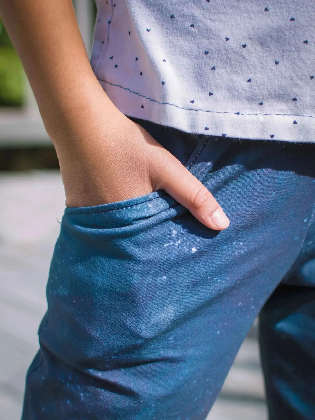 A person's hand is in the pocket of blue pants with a white speckled pattern.
