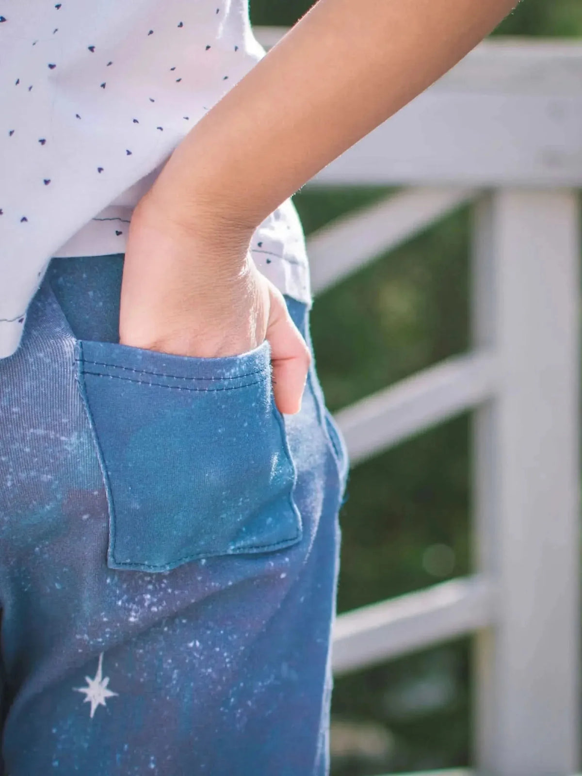 Blue fabric with white star and celestial print, hand in pocket.