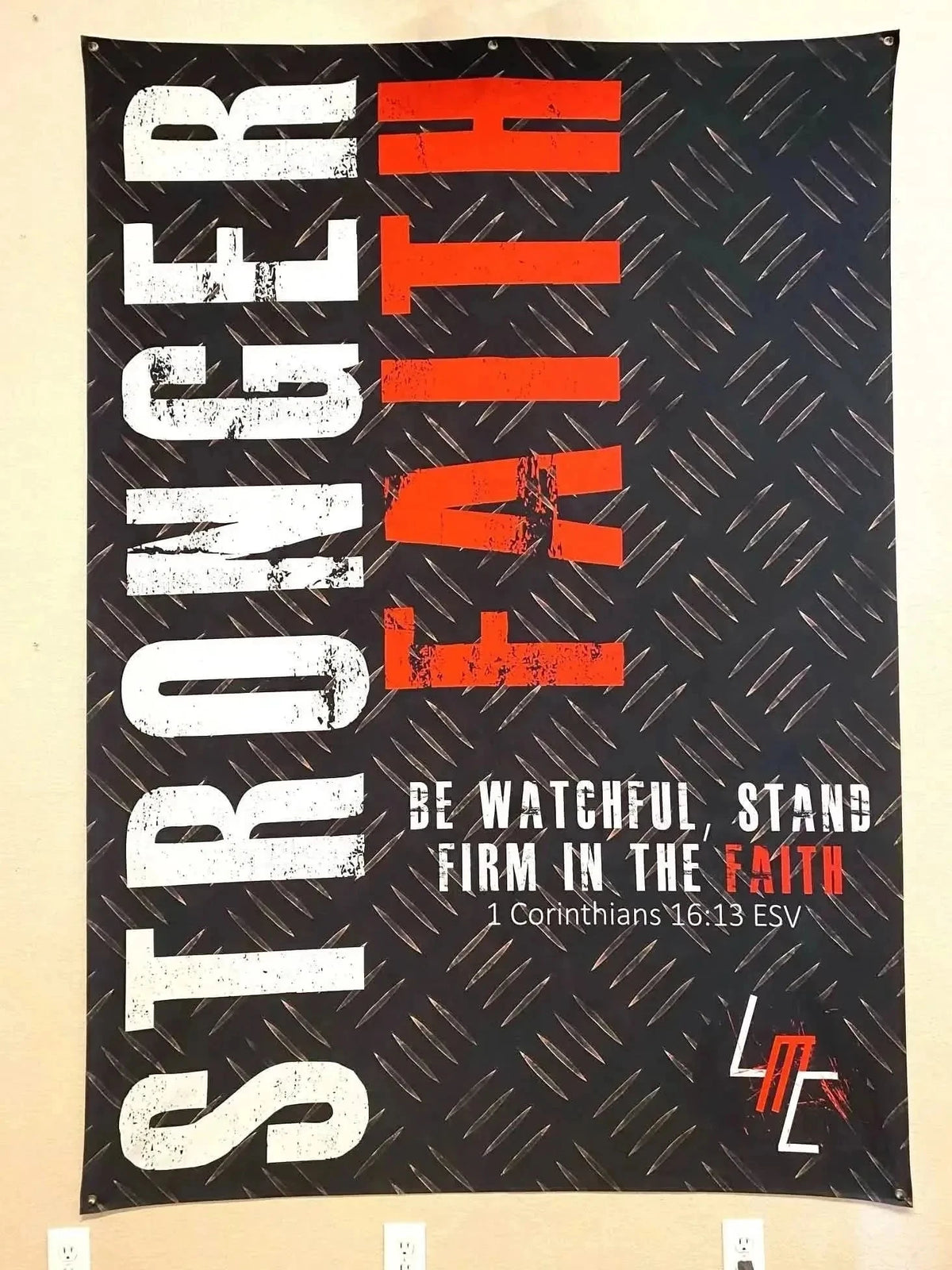 Black fabric banner with white "Stronger Faith" text and red "Be Watchful, Stand Firm in the Faith" Bible verse from 1 Corinthians 16:13 ESV.