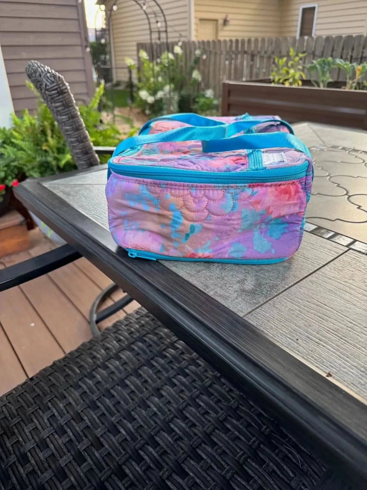 Purple fabric with glass flower pattern, shown as a lunch bag on a patio table.