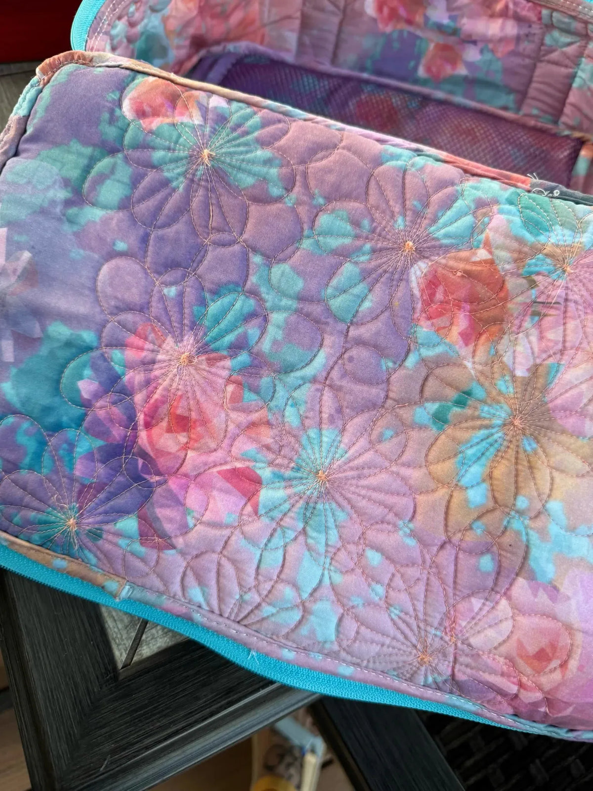 Quilted fabric with purple, pink, and teal floral patterns.