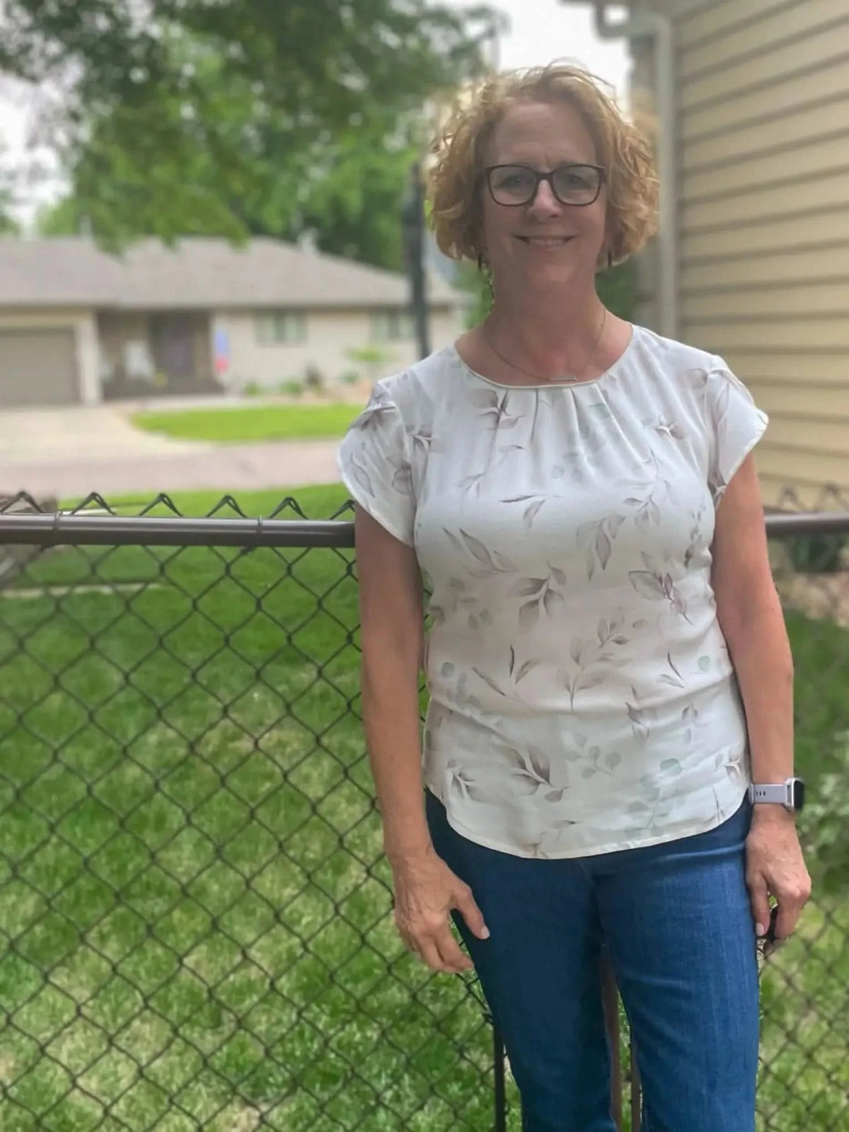A woman wears a white top with a subtle eucalyptus leaf pattern.