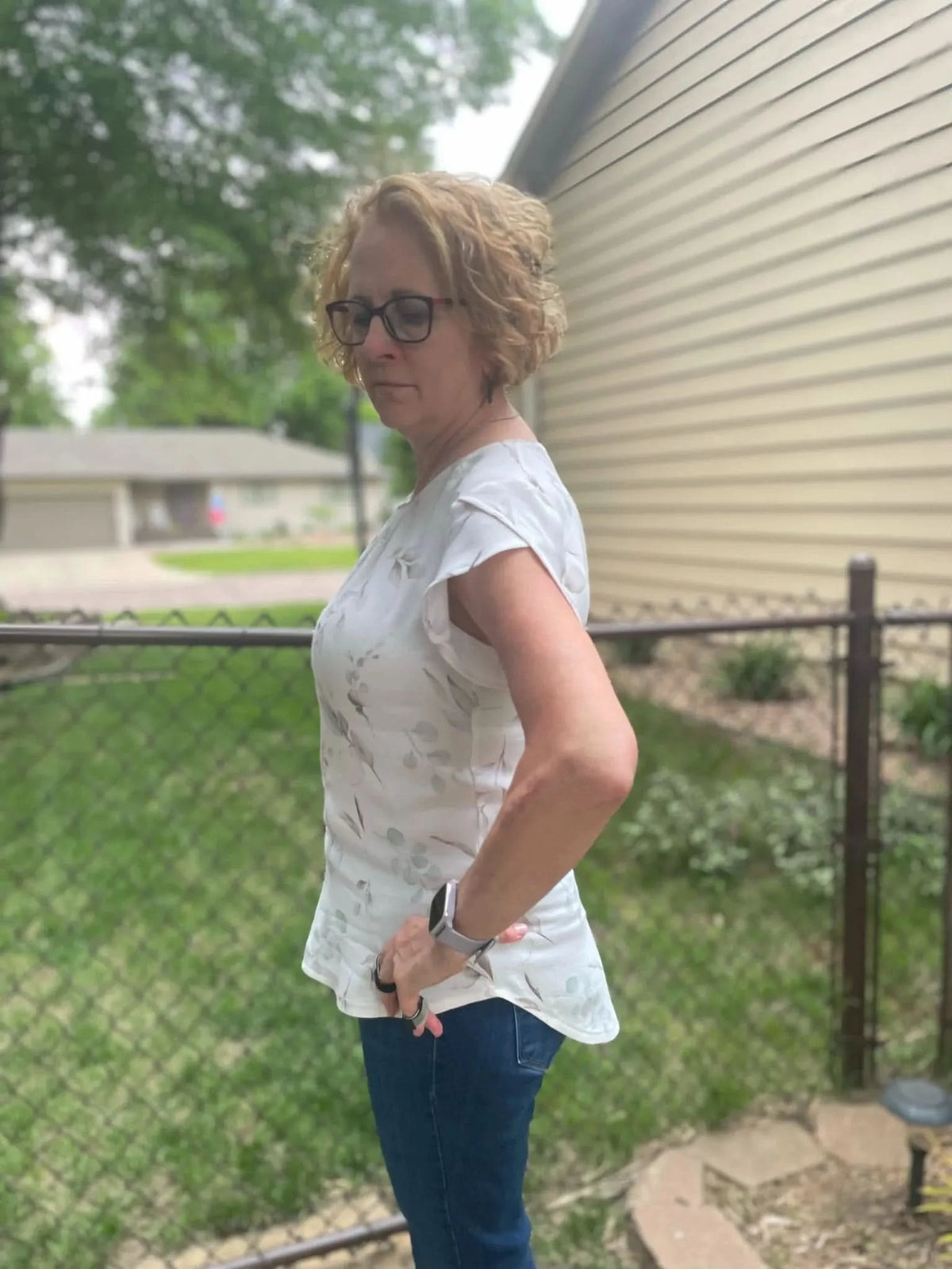 A woman models a white top with a subtle eucalyptus leaf pattern.