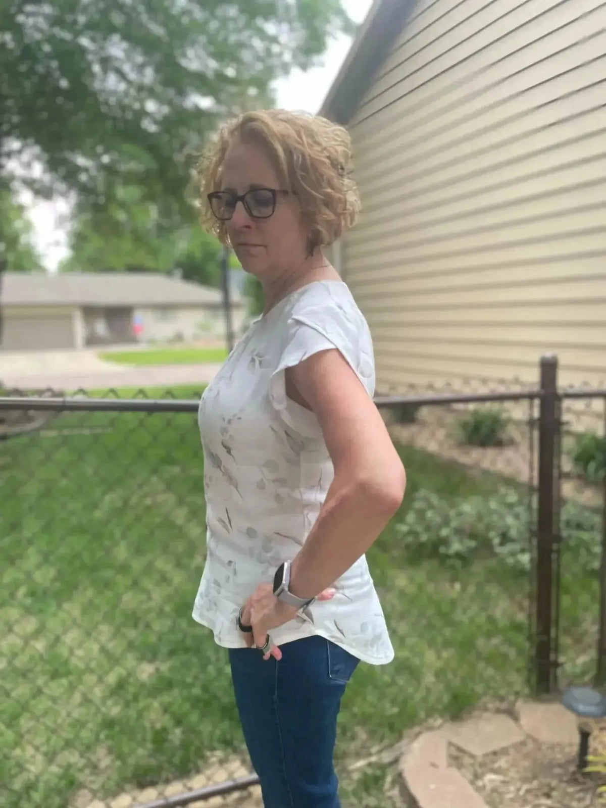 Woman modeling a white blouse with eucalyptus leaves botanical print, paired with jeans.