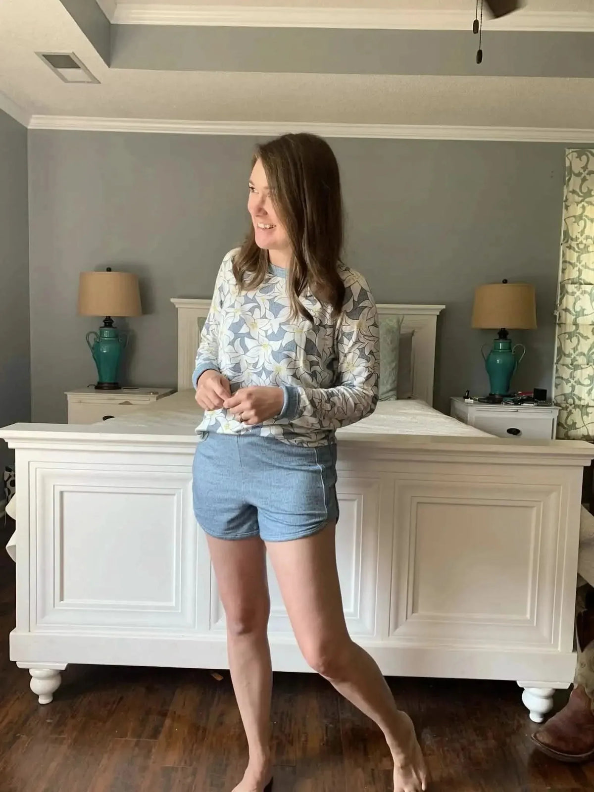 A woman wears a blue faith-based print long-sleeve top and blue shorts.