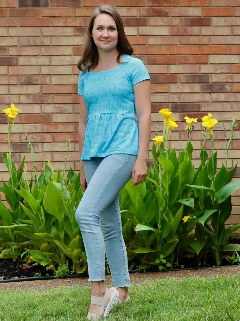 Woman in a blue peplum top with light blue jeans and nude sandals.