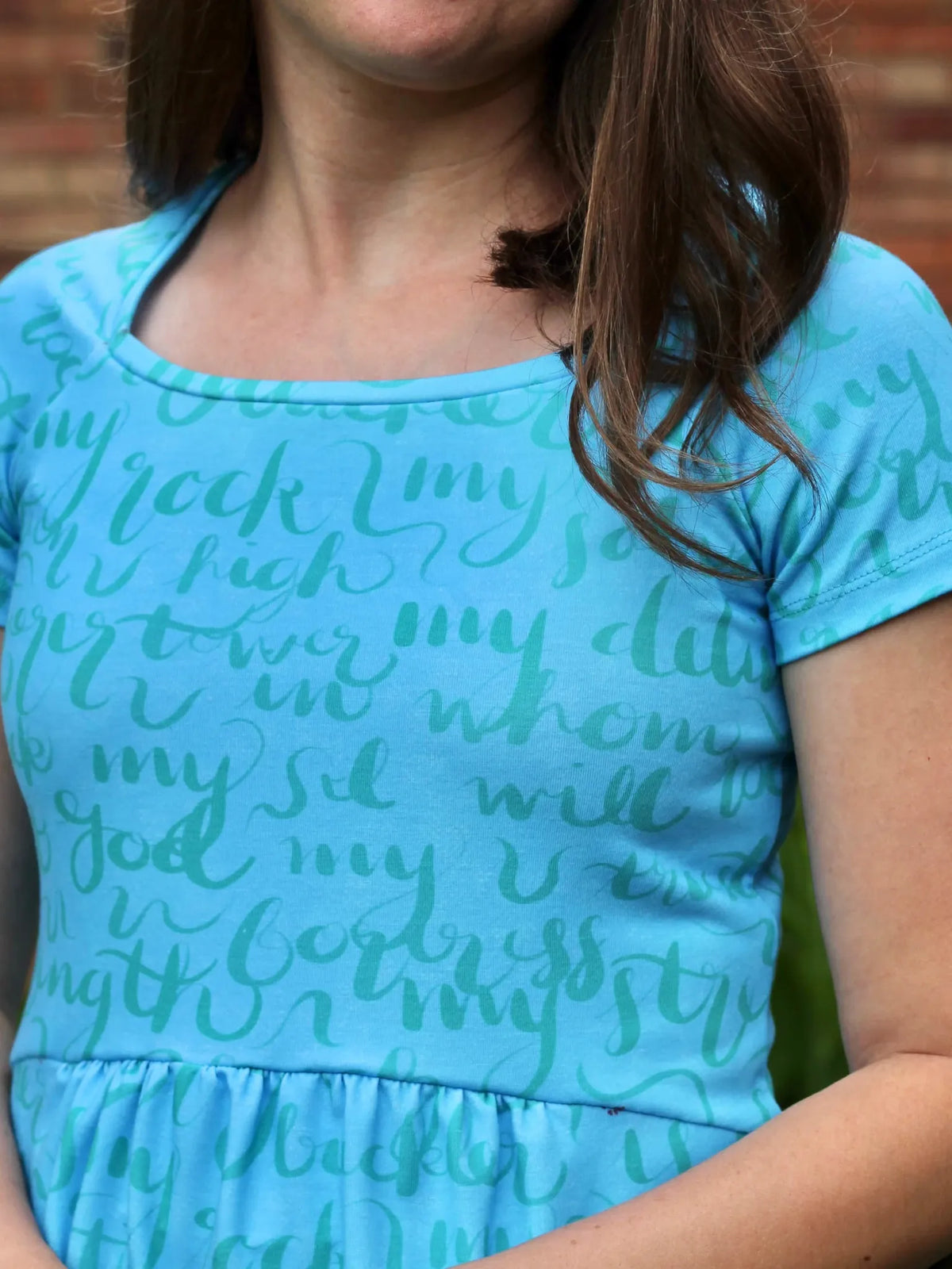 A woman wears a light blue dress with a darker blue script pattern.