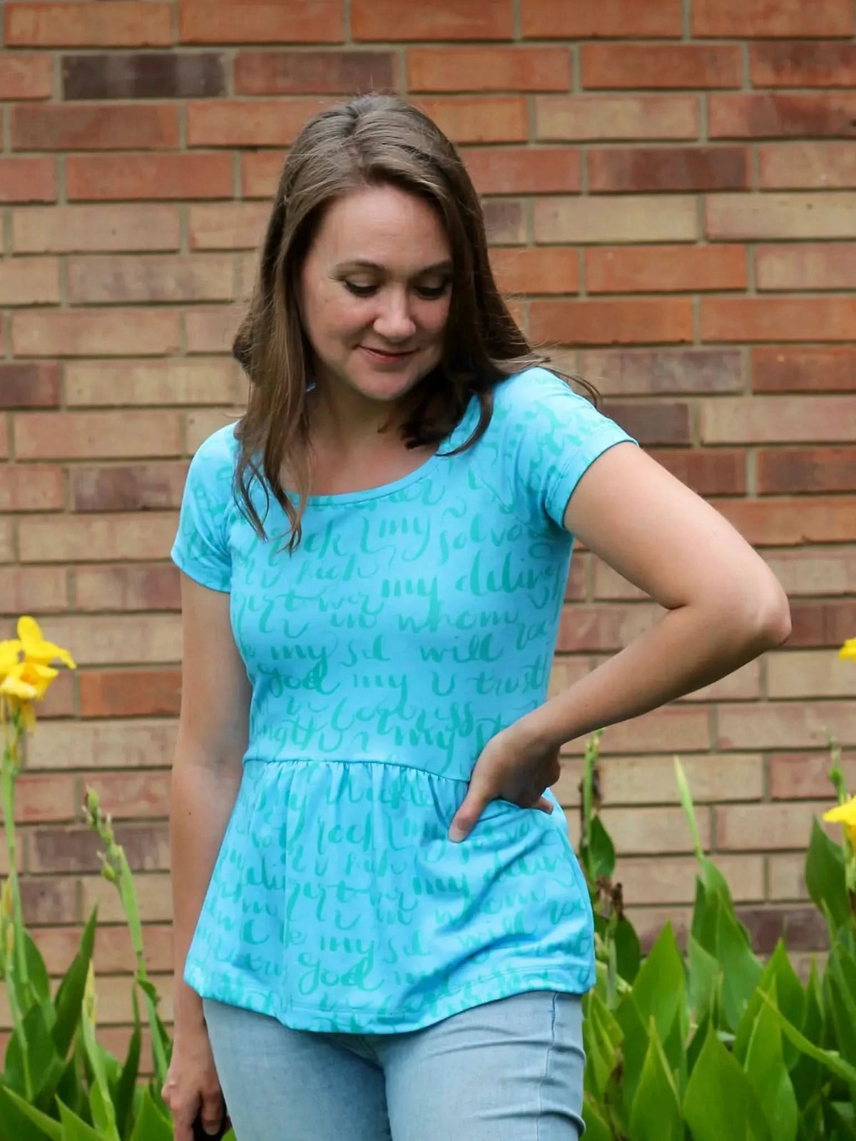A woman wears a blue top with light blue script and a peplum hem.