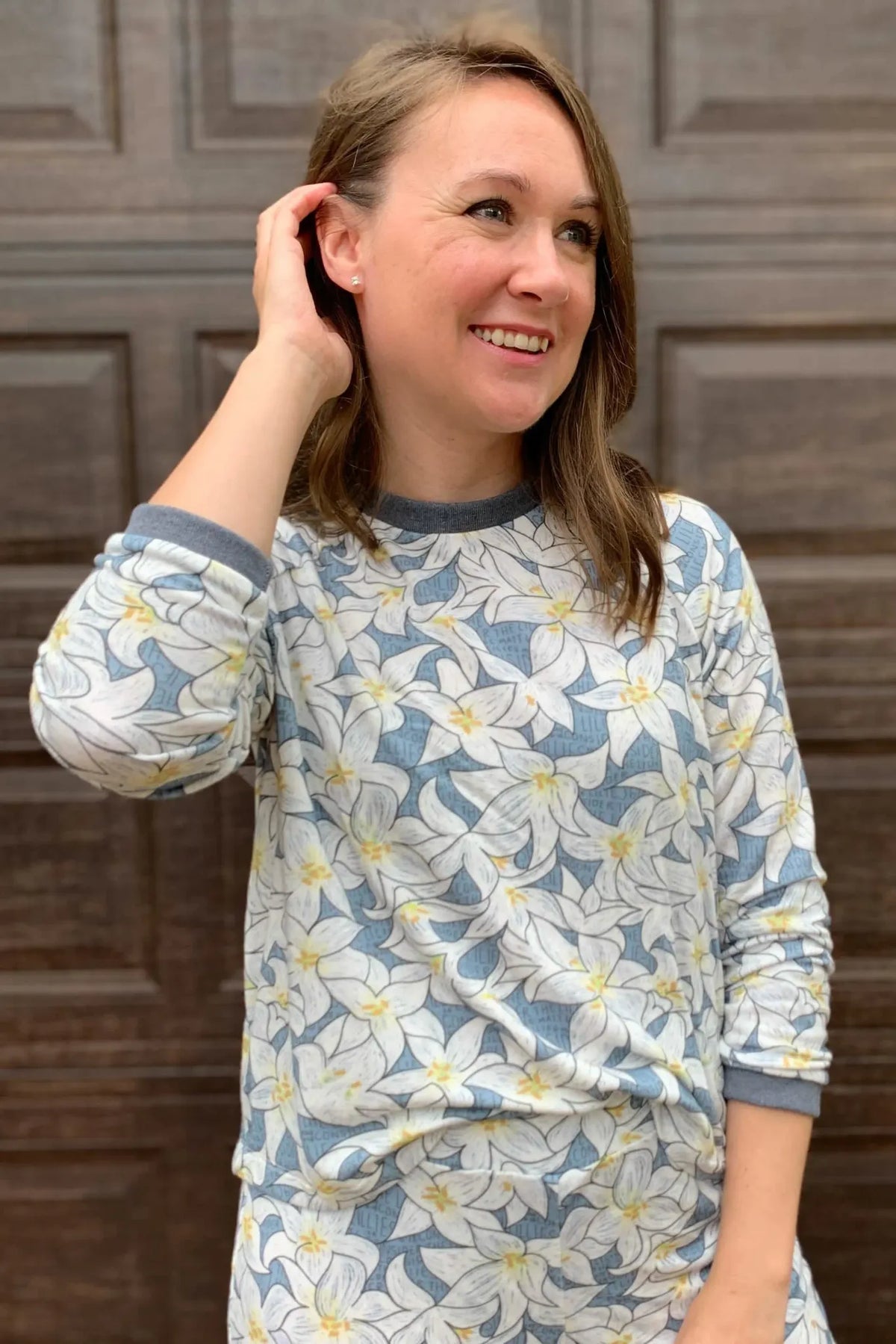 A woman wears a long-sleeved shirt with a blue and white lily floral pattern.