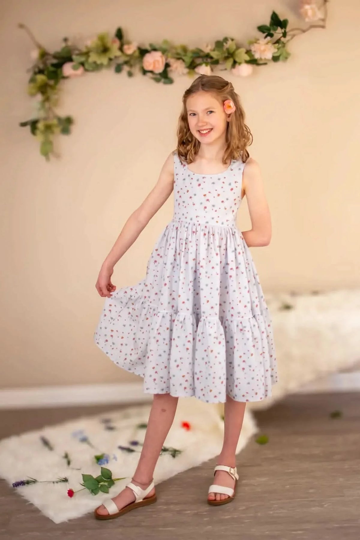A young girl in a light blue dress with small floral patterns and white sandals.