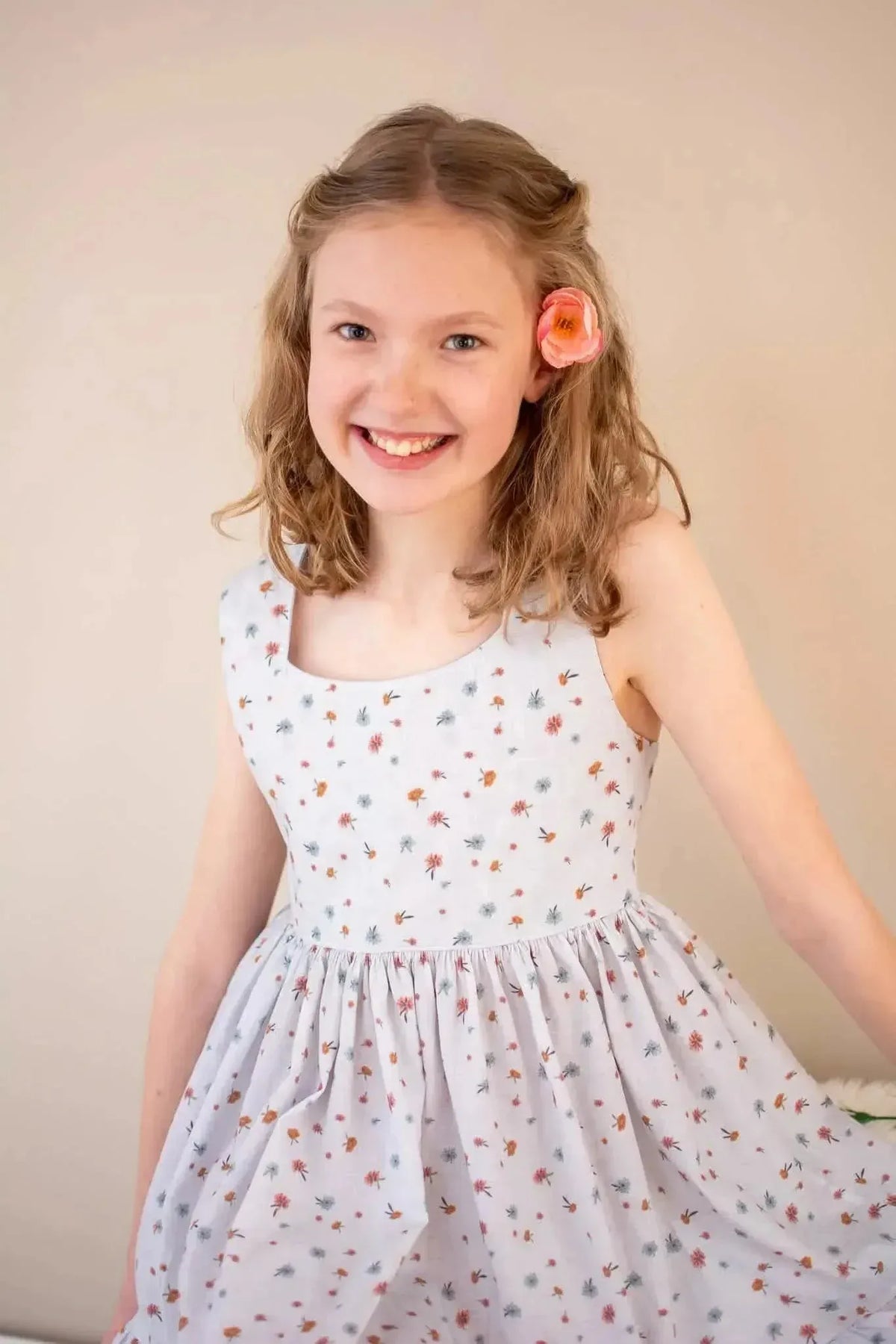 Light blue floral fabric with garden print and star motifs, shown in a girl's sleeveless dress.