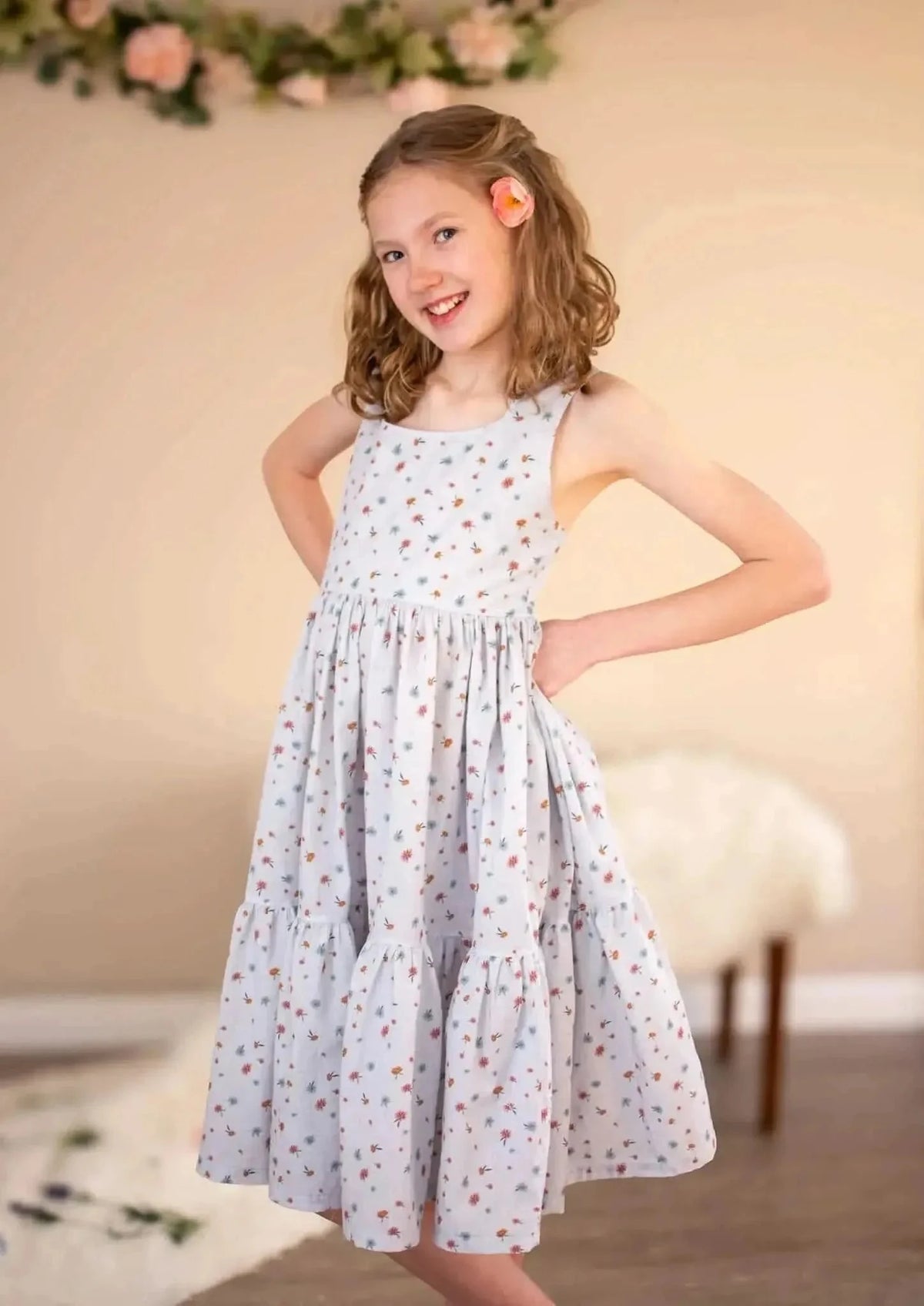 Light blue floral fabric with garden print on a girl's sleeveless tiered dress.