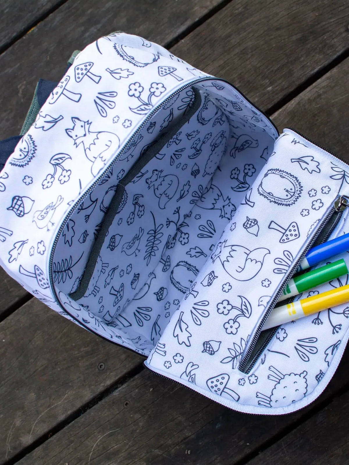 An open white bag with black woodland creature drawings and three markers inside.