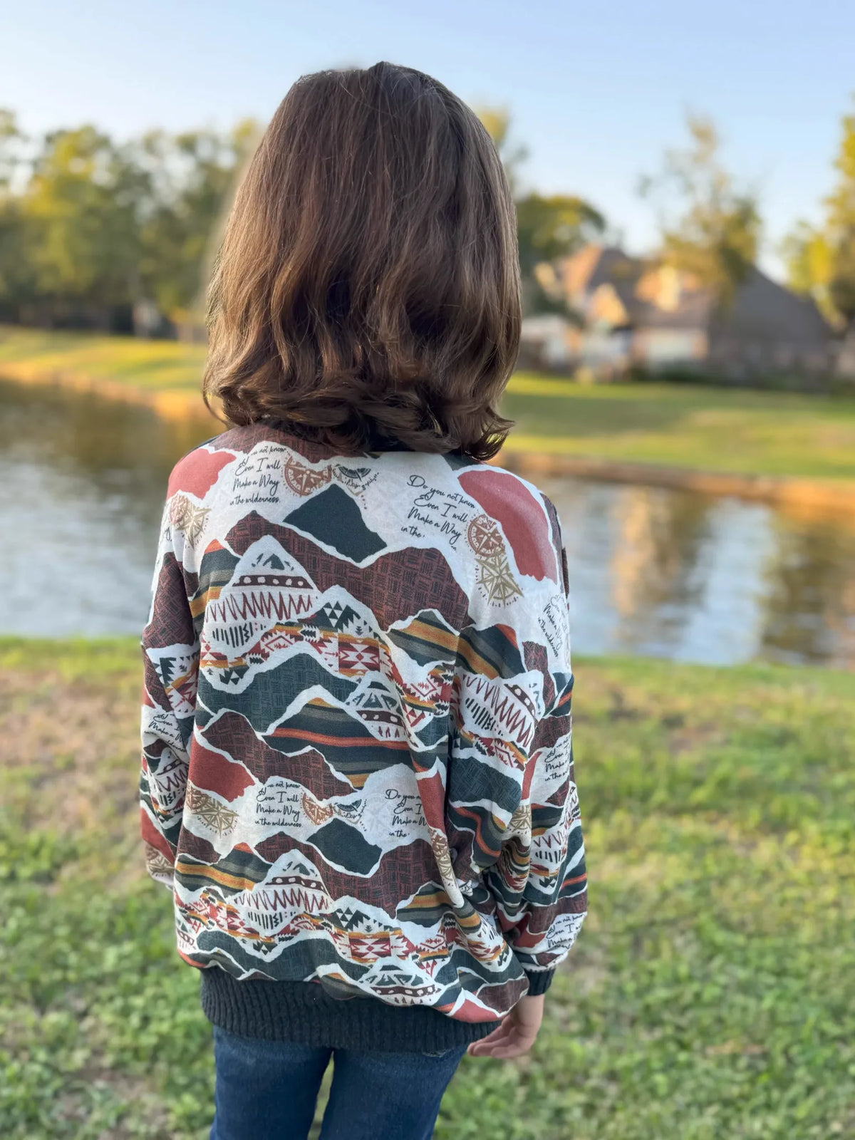 A person from behind wearing a patterned long-sleeve shirt with text.