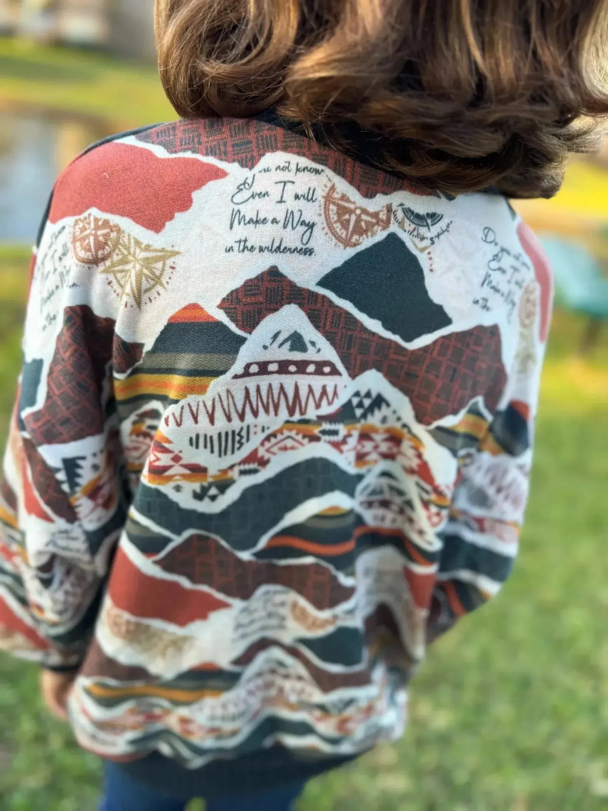 Rear view of a loose cardigan sweater in WayMaker faith-based print fabric with mountain patterns and "I will make a way" text.