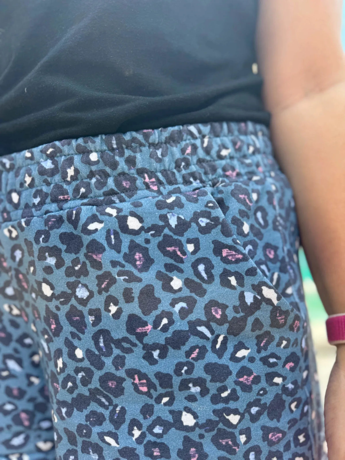 A person wears blue leopard print shorts with a black top.