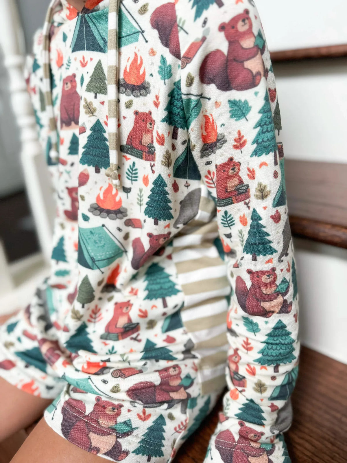 A child wears a hoodie and shorts with a camping bears pattern.