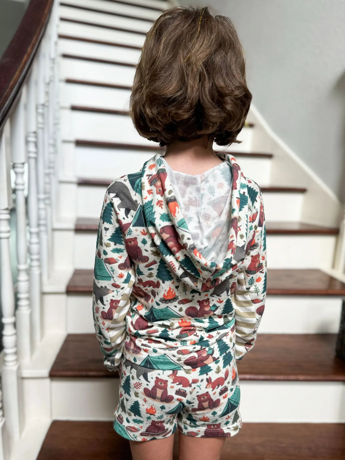 A child from behind wearing a camping bears hoodie and shorts set.