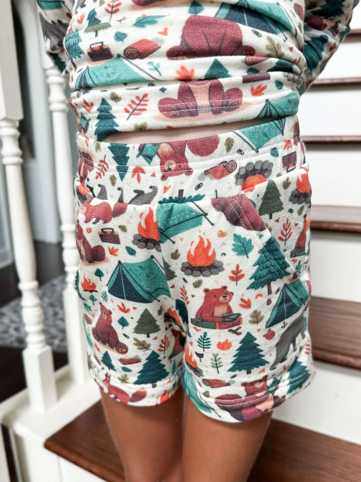 A child wears shorts with a camping bears print.