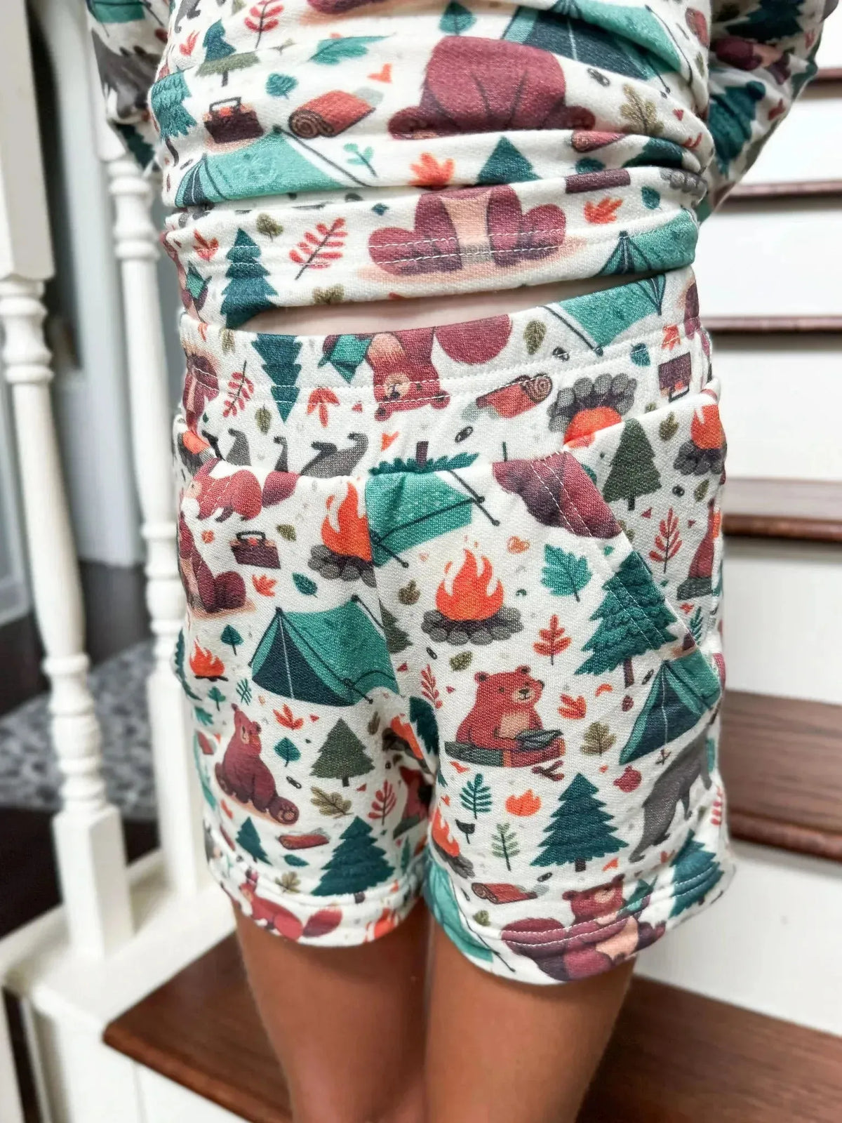 Fabric with woodland camping bears, tents, trees, and fire prints in green, red, and brown tones.