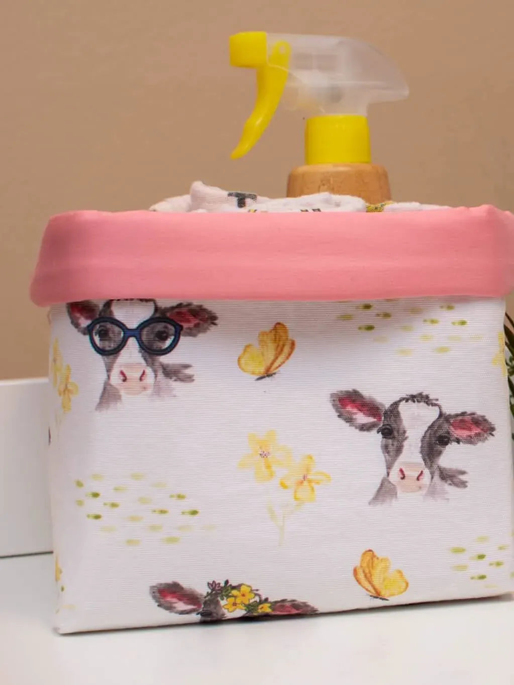 A fabric basket with a pink rim features watercolor calves, butterflies, and flowers.