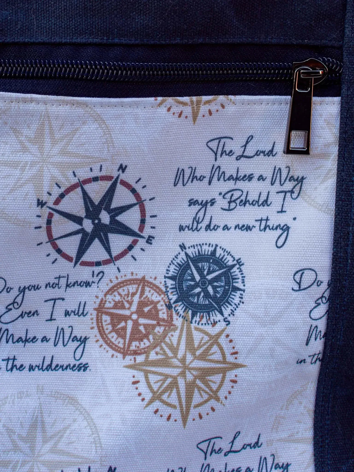 A white fabric with compass designs and text, featuring a black zipper.