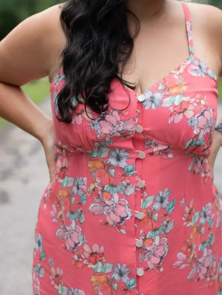 A woman in a coral floral dress with white buttons down the front.