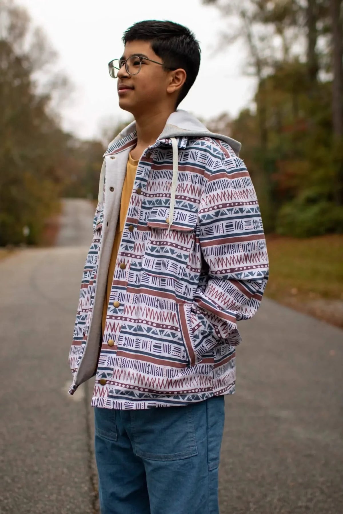 A person wearing a Desert Echoes patterned jacket with a yellow shirt and blue jeans.