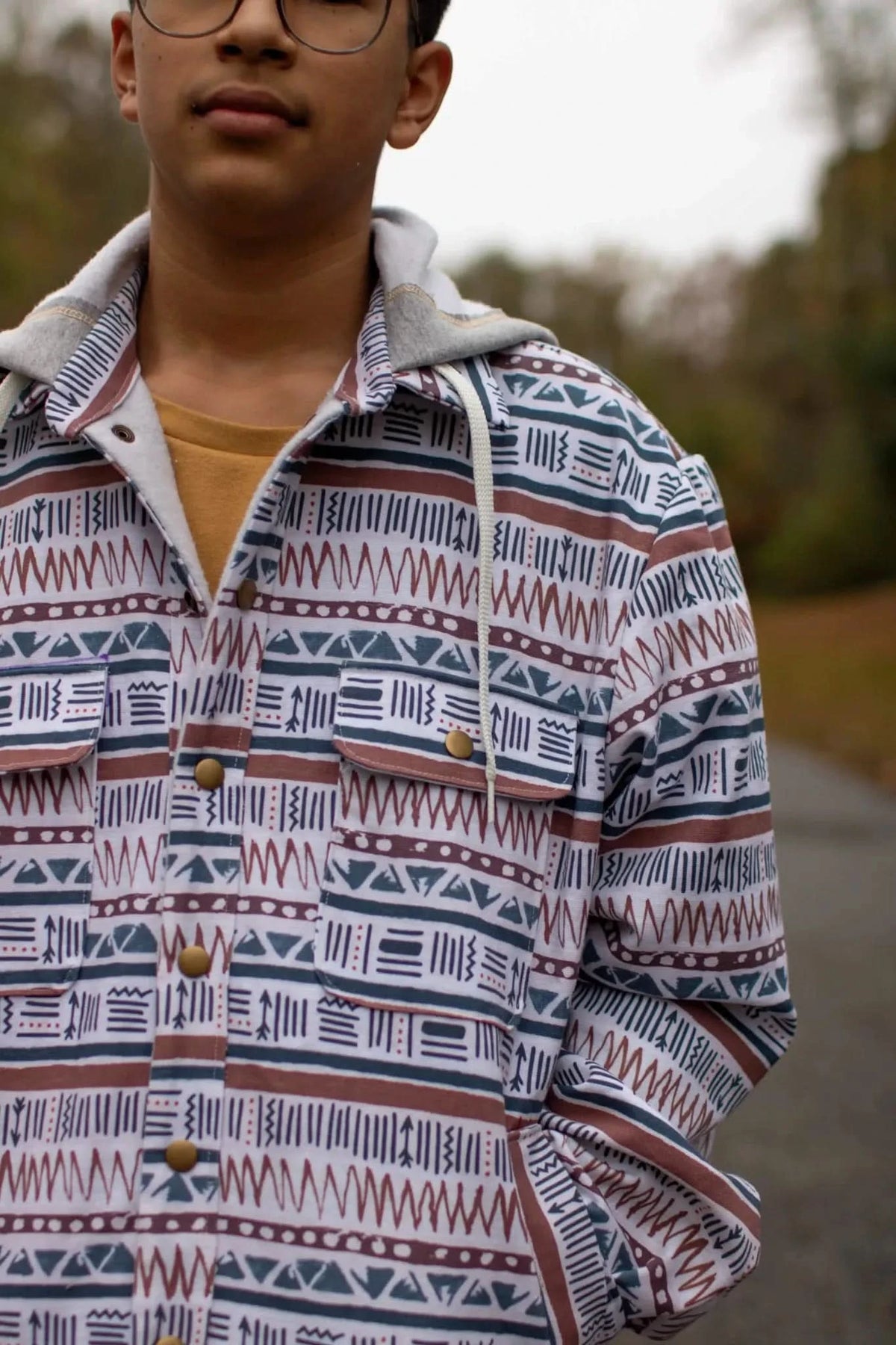 A person wears a hooded jacket with a desert-themed pattern.