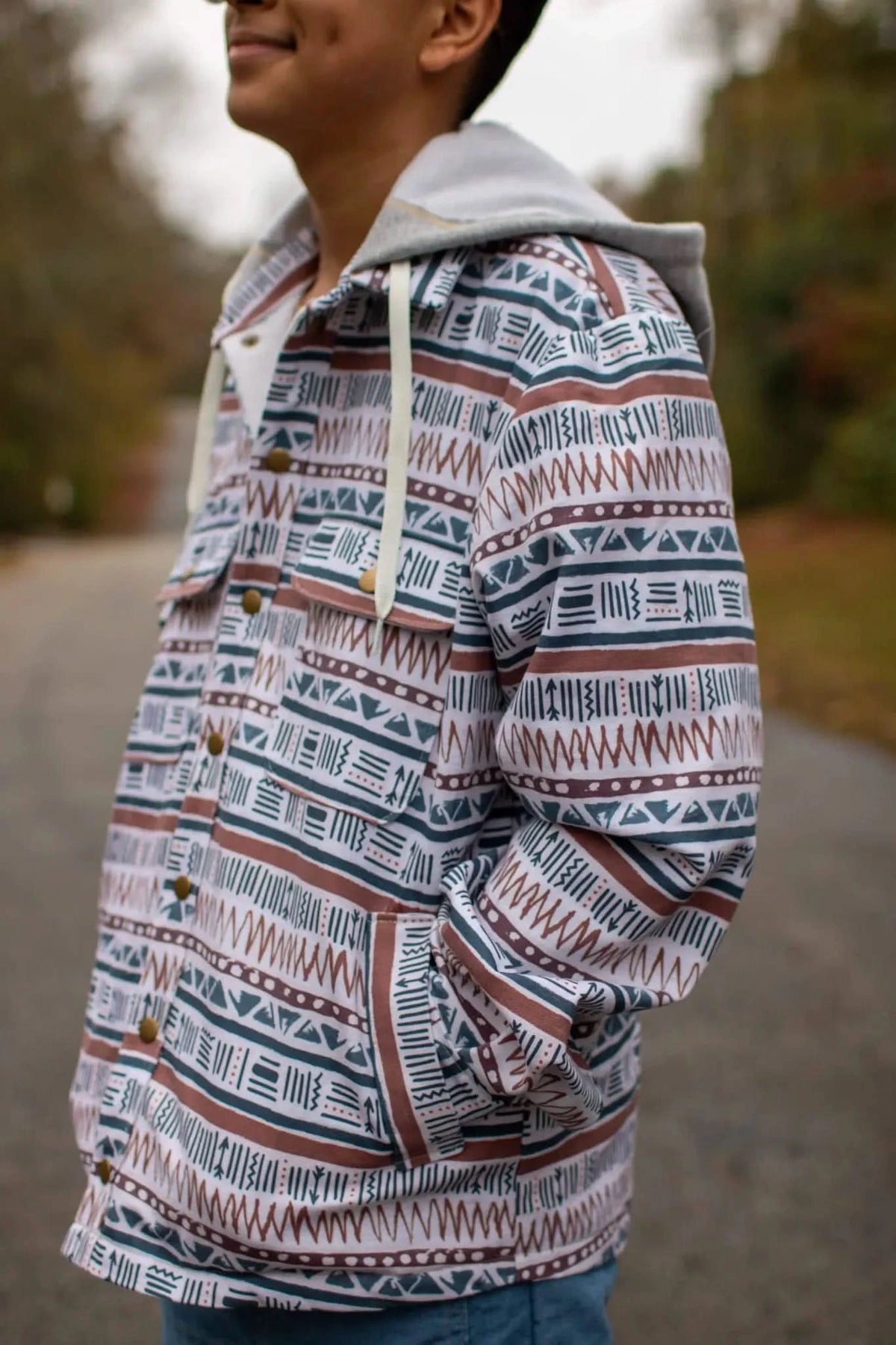 A person wears a hooded jacket with a brown, blue, and white geometric pattern.