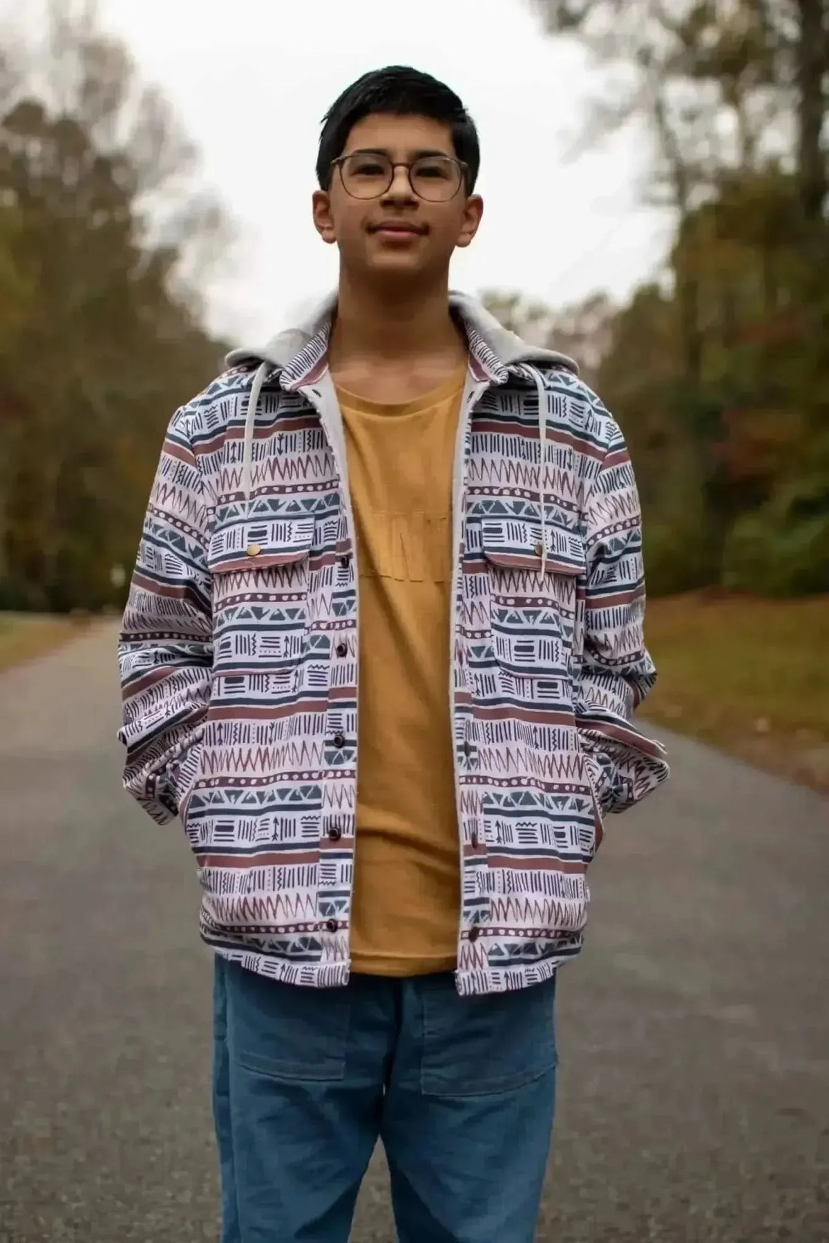 Young man wearing a patterned hoodie jacket made from Desert Echoes Faith-Based Fabric, standing outdoors.
