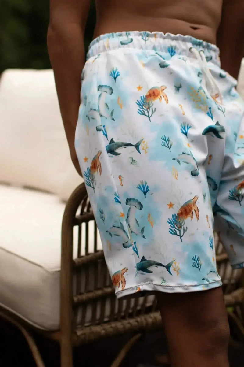 Blue aquatic print fabric featuring sea creatures like fish, sharks, and coral on white background.