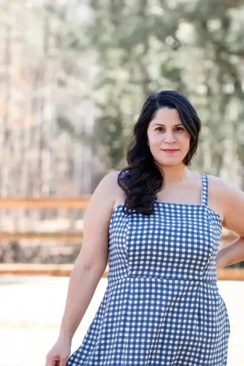 A woman in a navy and white gingham dress smiles at the camera.