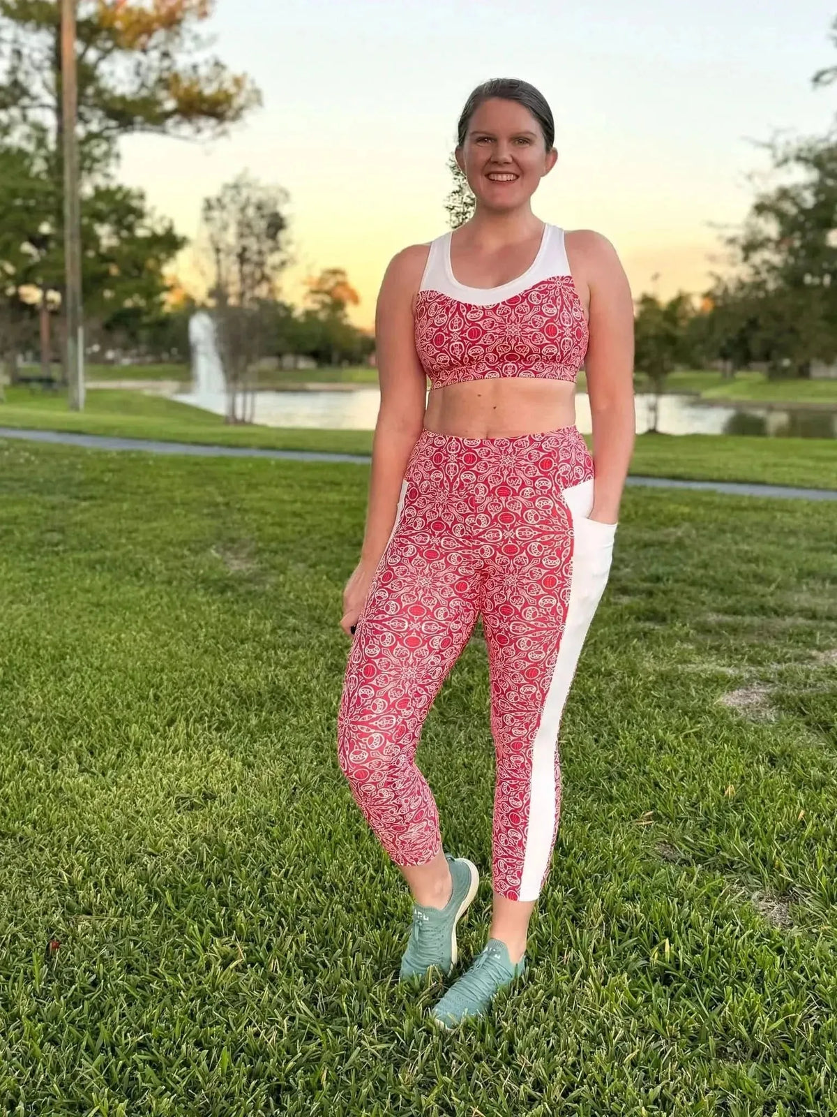 A woman wears a red and white patterned athletic top and matching leggings with white side panels.