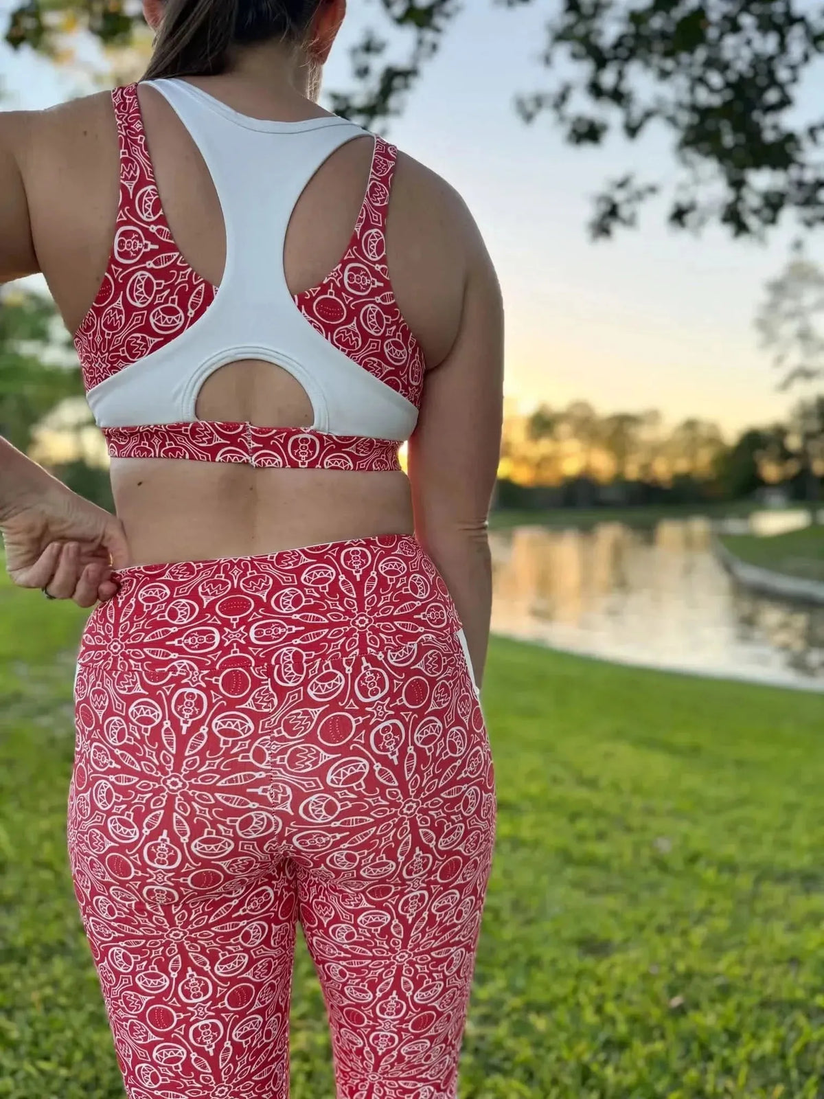 Red athletic leggings and sports bra with white floral holiday print, worn outdoors.